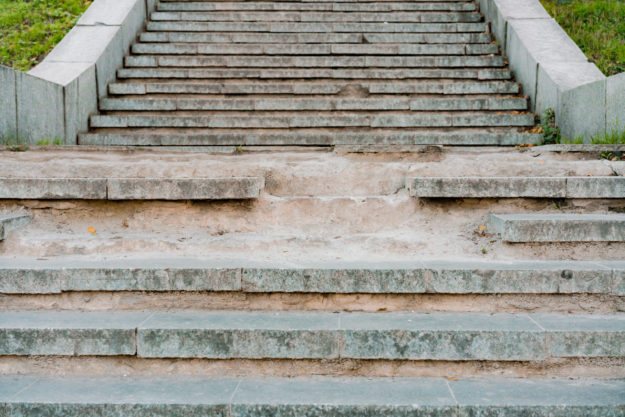 Big broken stairs in the the park made from concrete. Dangerous. Unsafe. Warning. Step. Abandoned. Public space. Bad. Need a repair. Poorness. City. Urban