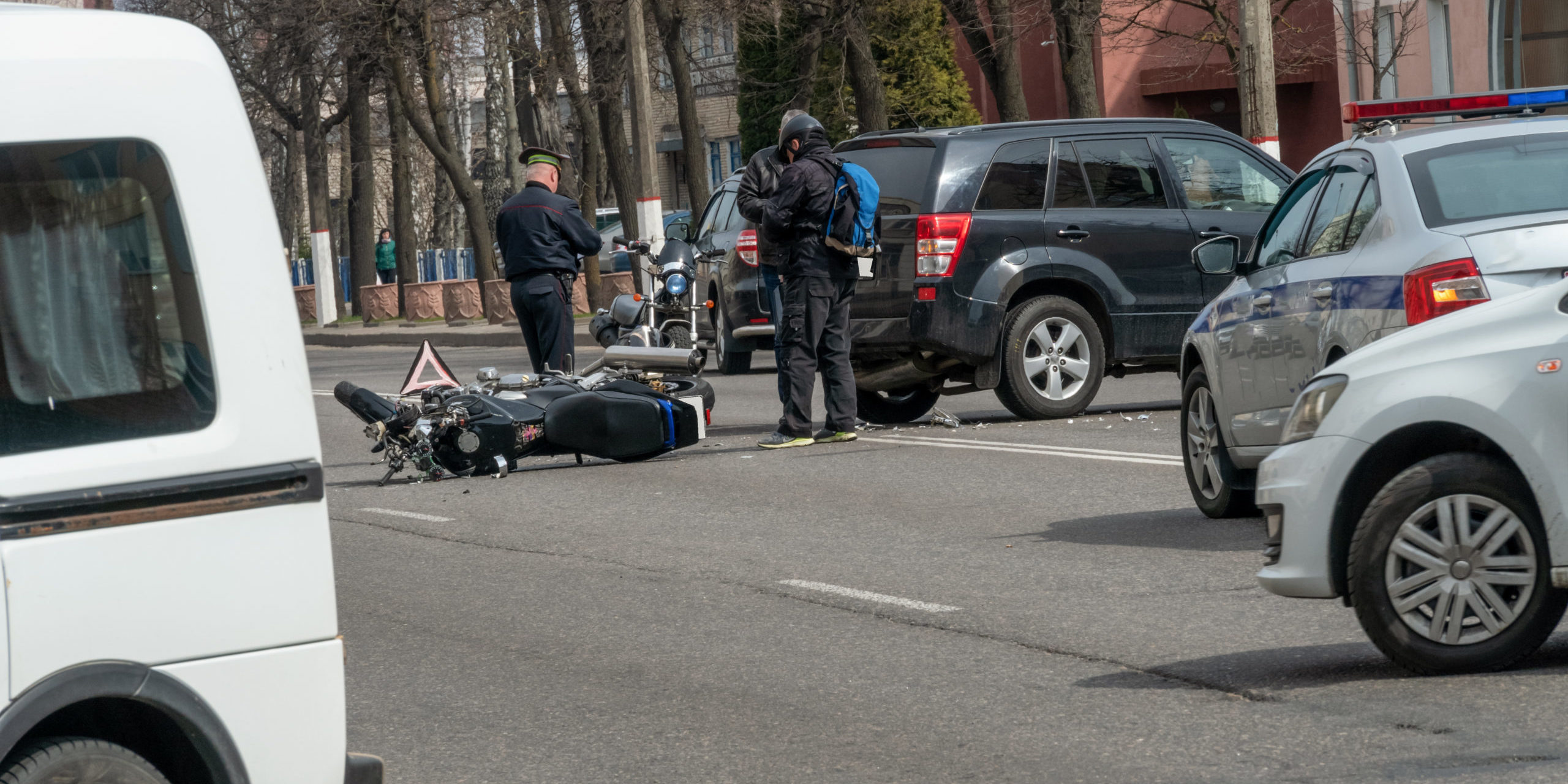 Accident in the city: a broken motorcycle and a car. Registration of a traffic accident. Traffic jam due to an accident, police car, police, people