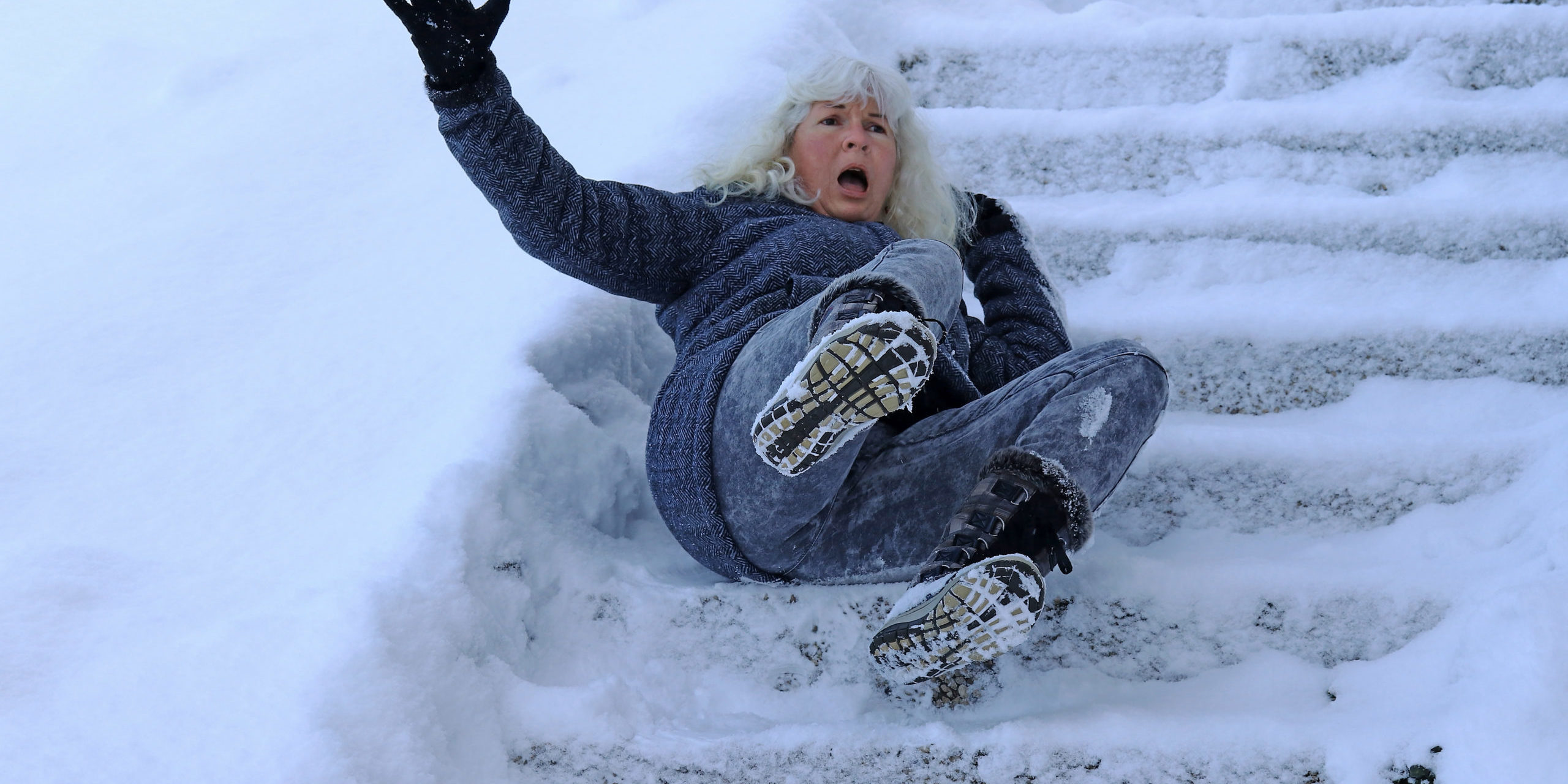 Eine Frau ist auf einer schneeglatten Treppe ausgerutscht und hingefallen